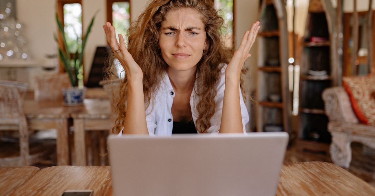 A woman looking confused and frustrated while checking something on her laptop