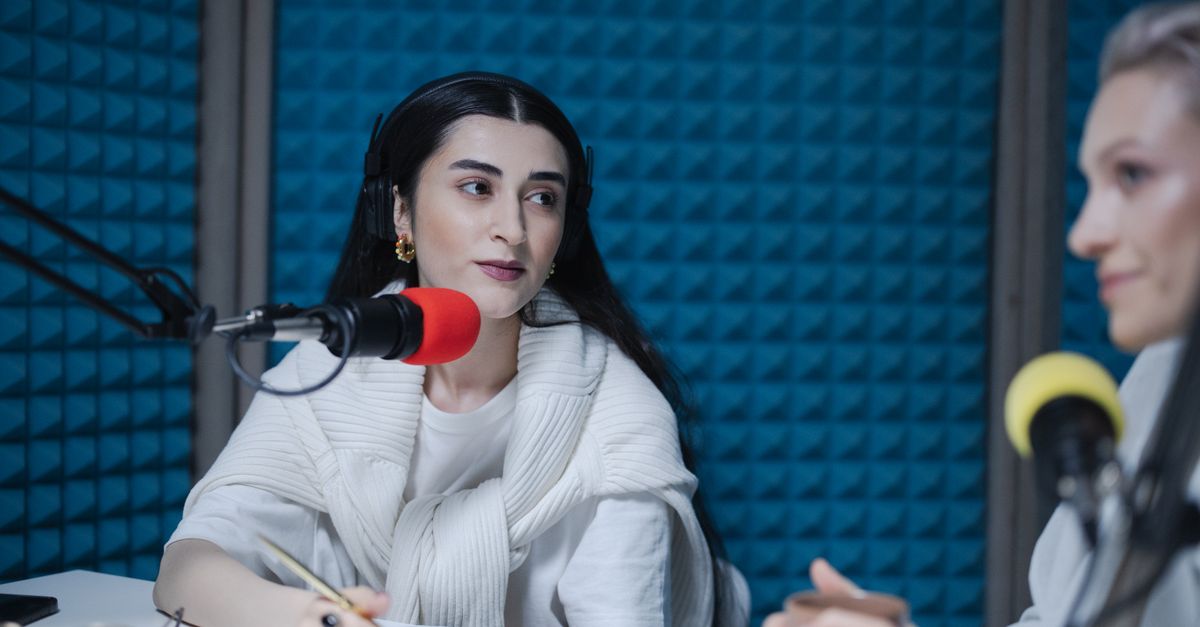 Two people recording a podcast together with professional microphones in a studio